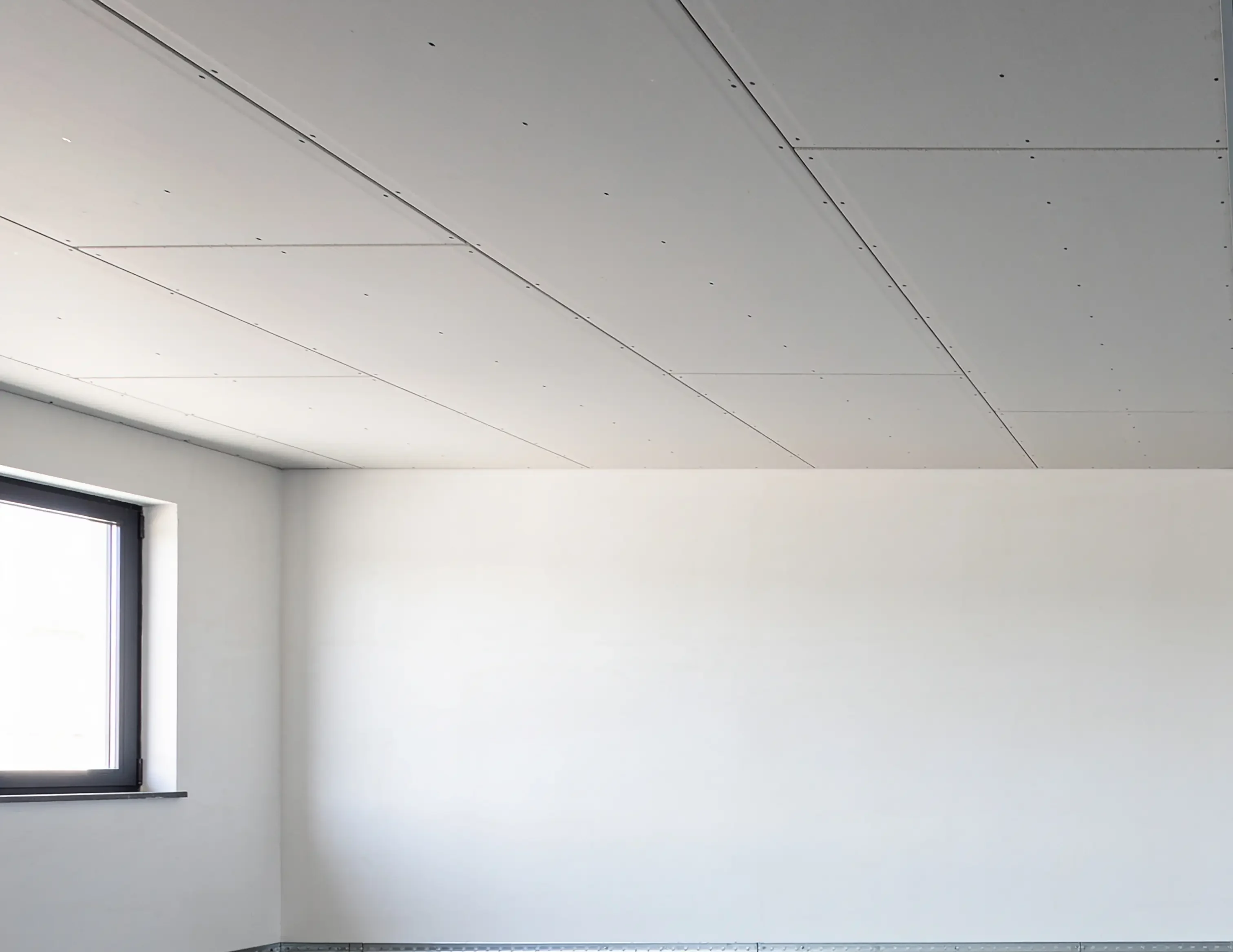 Fertig beplankte Decke aus Gipsplatten in einem leeren Raum im Rohbau