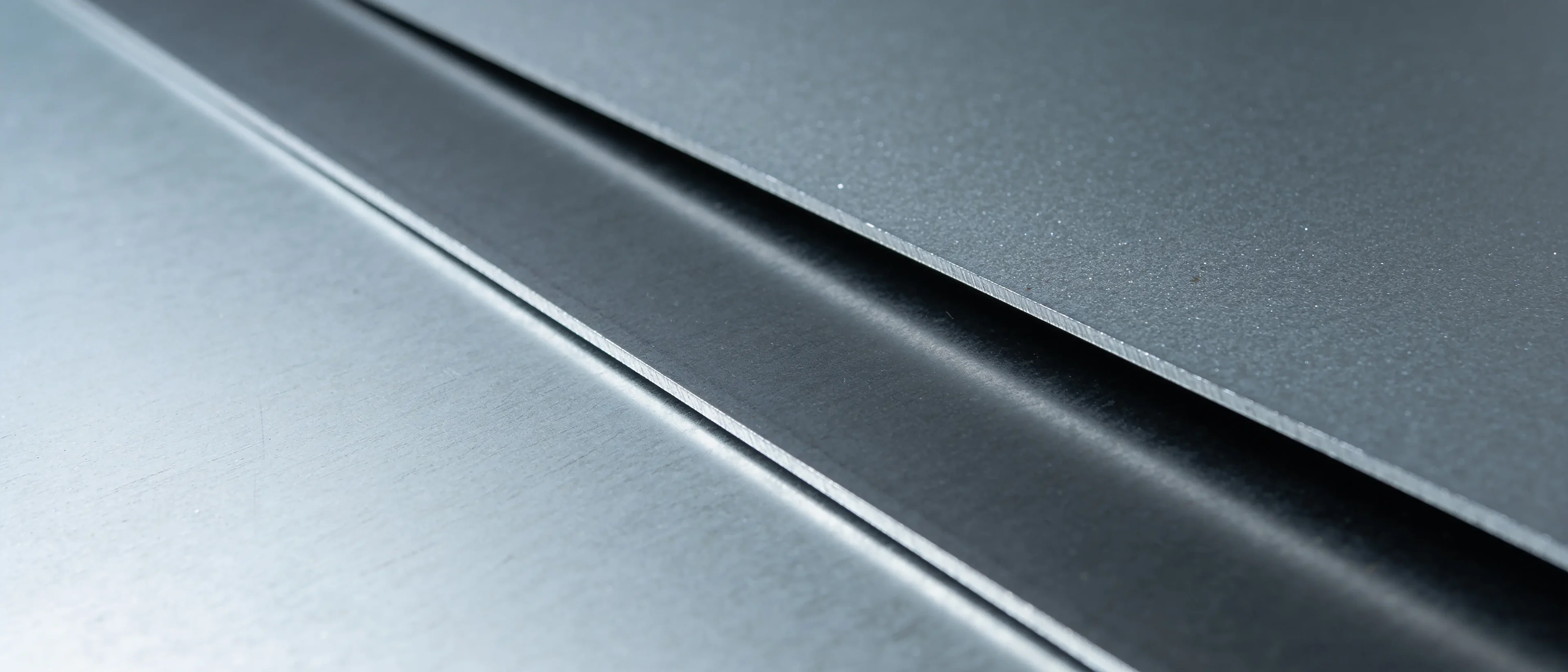 Zwei Stahlbleche mit metallischer Beschichtung und Schnittkante in Nahaufnahme